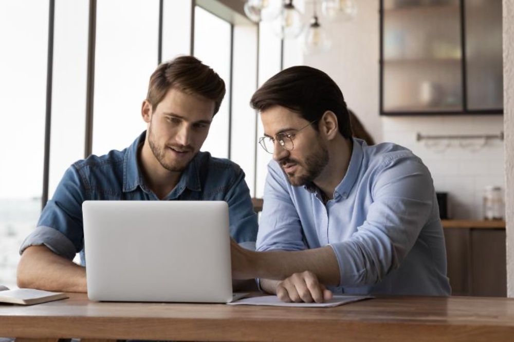 2 professionals working with each other on laptop